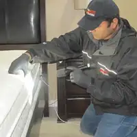 Bed bug inspection technician checking a mattress and bed frame for signs of infestation in Dover, DE