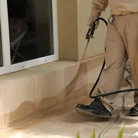 General pest control technician spraying exterior perimeter around a home in Dover, DE