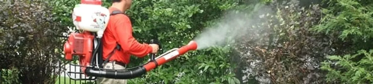 Mosquito control technician fogging shrubs and landscaping for mosquito treatment in Dover, DE