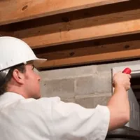 Termite inspection technician checking a basement wall and framing for termite activity in Dover, DE