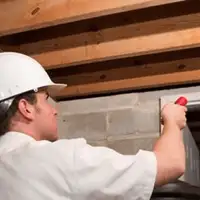 Termite inspection technician checking a basement wall and framing for termite activity in Dover, DE